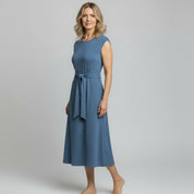 woman wearing blue maxi dress on a plain background
