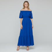 woman wearing blue off shoulder maxi dress on a plain background