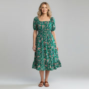 woman wearing green floral maxi dress on a plain background