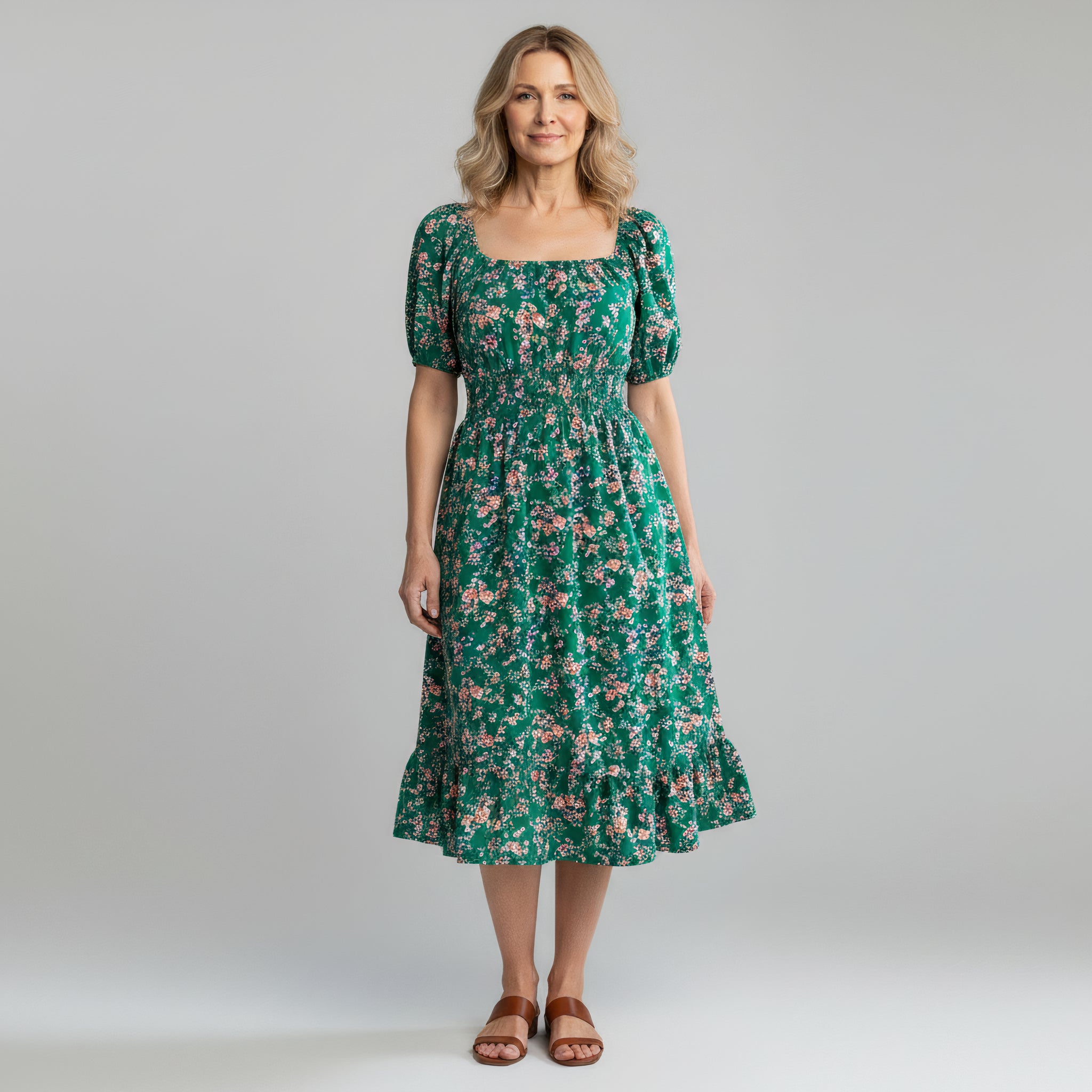 woman wearing green floral maxi dress on a plain background