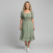 woman wearing light green floral maxi dress on a plain background