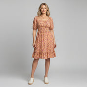 woman wearing yellow floral print maxi dress on a plain background