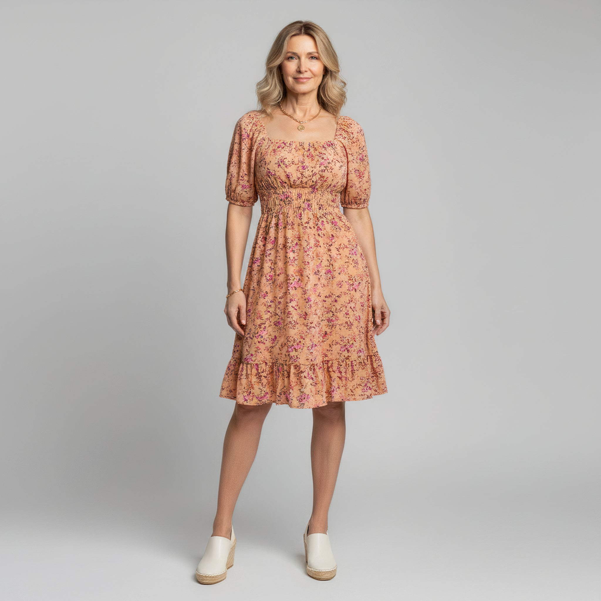 woman wearing yellow floral print maxi dress on a plain background