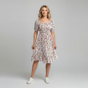 woman wearing white floral print maxi dress on a plain background