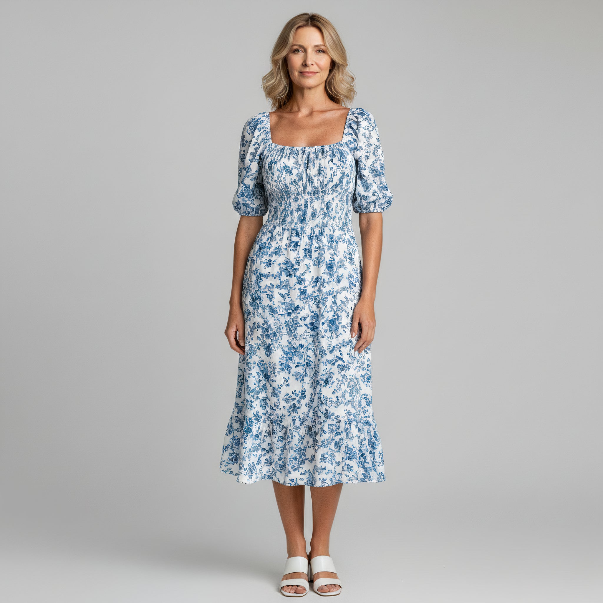 woman wearing blue floral print maxi dress on a plain background