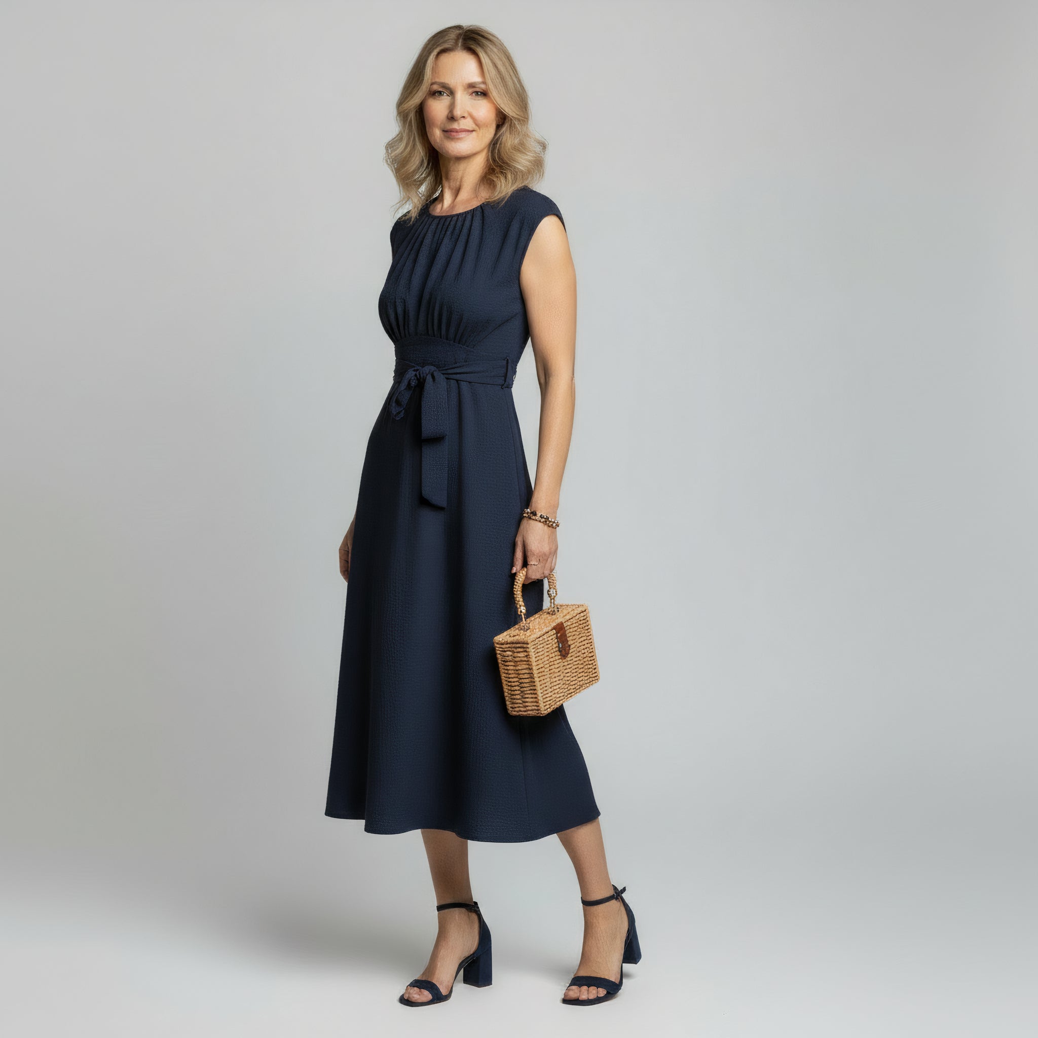 woman wearing navy blue sleeveless maxi dress on a plain background 