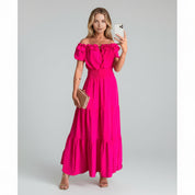 woman wearing pink off shoulder maxi dress on a plain background